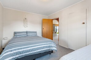 Ein Schlafzimmer mit Bett, Nachttisch und einer Tür zu einem weiteren Raum.