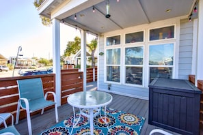 A covered outdoor area with a deck, a glass table, and a bench. - The Bluebonnet Bungalow with Resort Access (Austin)