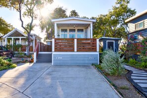 A modern house with a front porch, a garage, and a small garden. - The Bluebonnet Bungalow with Resort Access (Austin)