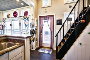 A kitchen with a granite countertop, a stainless steel sink, and a variety of hanging items including pots and pans. - The Bluebonnet Bungalow with Resort Access (Austin)
