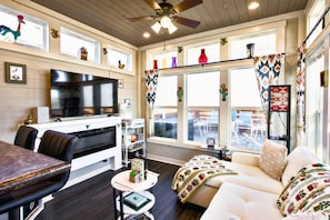 A cozy living room with a flat-screen TV, a sofa, a coffee table, and a dining area with a table and chairs. - The Bluebonnet Bungalow with Resort Access (Austin)