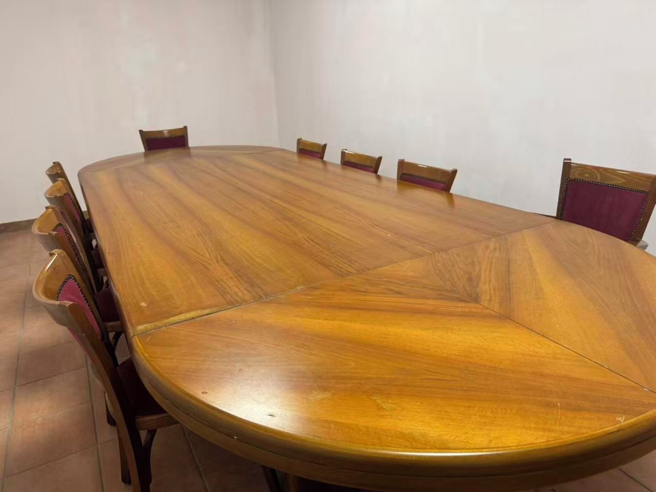 Une table de conférence entourée de six chaises, un sol carrelé et des murs aux couleurs neutres.