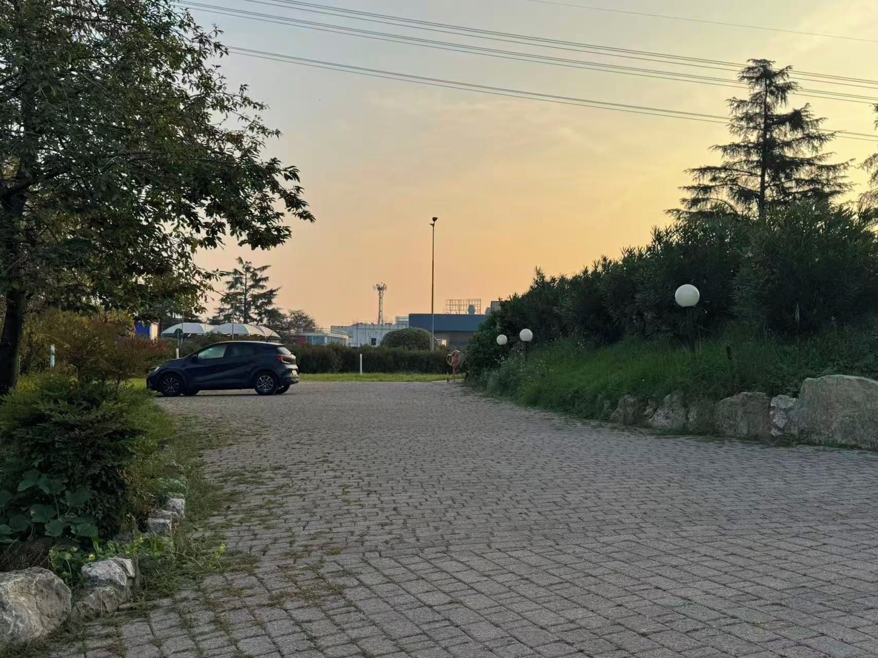 Une allée pavée mène à un bâtiment devant lequel est garée une voiture.