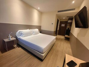 A hotel room with a bed, bedside table, and a flat-screen TV mounted on the wall. - aurora hotel (Trezzano Rosa)