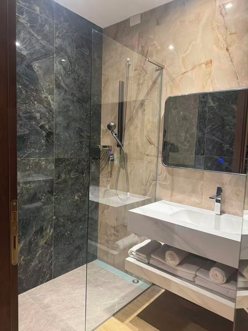 A modern bathroom with a glass-enclosed shower, a white vanity, and a mirror above the sink.