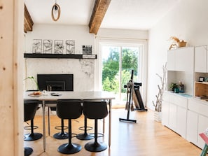 A modern kitchen with a marble countertop, black bar stools, and a large window.