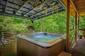 Un bain à remous sur une terrasse en bois, avec vue sur une forêt.