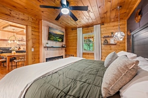 L'intérieur d'un chalet en bois, avec un lit, un coin repas et une cheminée.