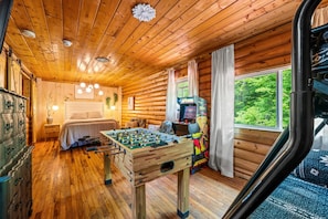 Ein gemütliches Zimmer mit einem Bett, einem Tischfußballtisch und einem Fenster mit Blick auf Grünflächen.