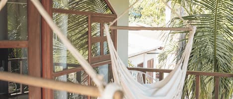 A hammock hanging in a room with wooden floors and large windows.