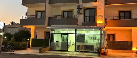 Un hotel de varios pisos con entrada a nivel de calle, balcones en cada planta y un letrero visible con el nombre del hotel.