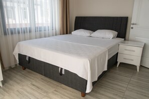 A bedroom with a bed, a nightstand, and a door. - Taşucu köylü pansiyon (Taşucu)