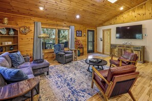 Uma sala de estar aconchegante com sofá, poltronas, televisão e lareira.