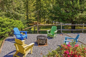 A patio area with Adirondack chairs, a fire pit, and a wooden fence. - Whispering Pines Retreat - Fire Pit - 2BR 2BTH (Rutherfordton)
