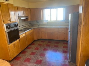 A kitchen with wooden cabinets, a stove, a refrigerator, and a window with curtains. - Pet friendly 3-bedroom house in Clarendon next to Allegheny national forest (Clarendon)