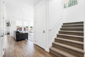 Ein modernes Interieur mit Holzboden, einer Couch, einer Treppe und einer Tür zu einem Außenbereich.