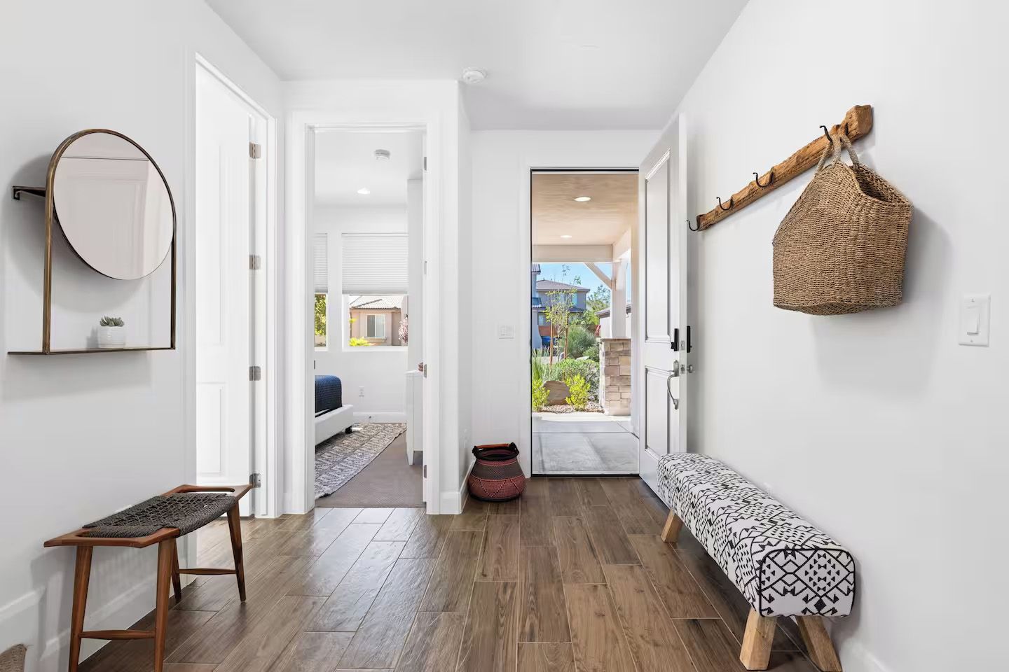 A hallway with a bench, a mirror, and a hanging basket.