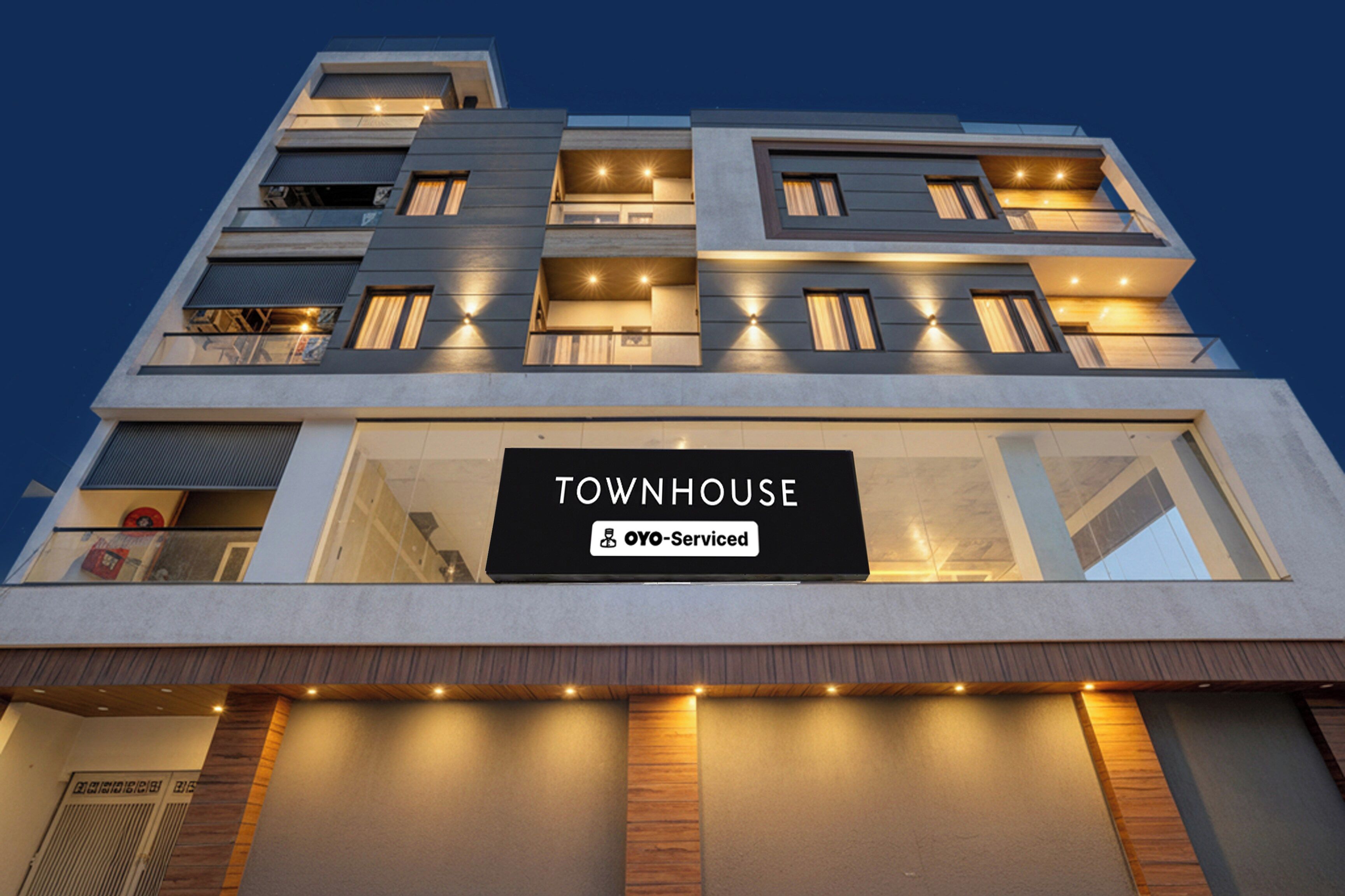 Un edificio de varios pisos con un letrero que dice 'TOWNHOUSE' y 'OYO-Serviced'.