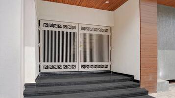 Une paire de portes à double battant, ornée d’un motif géométrique, qui donne sur un escalier en pierre.