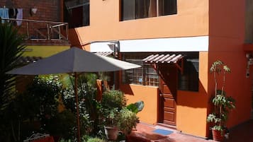 Un patio con una zona de estar techada, plantas en macetas y una escalera que lleva a un nivel superior.