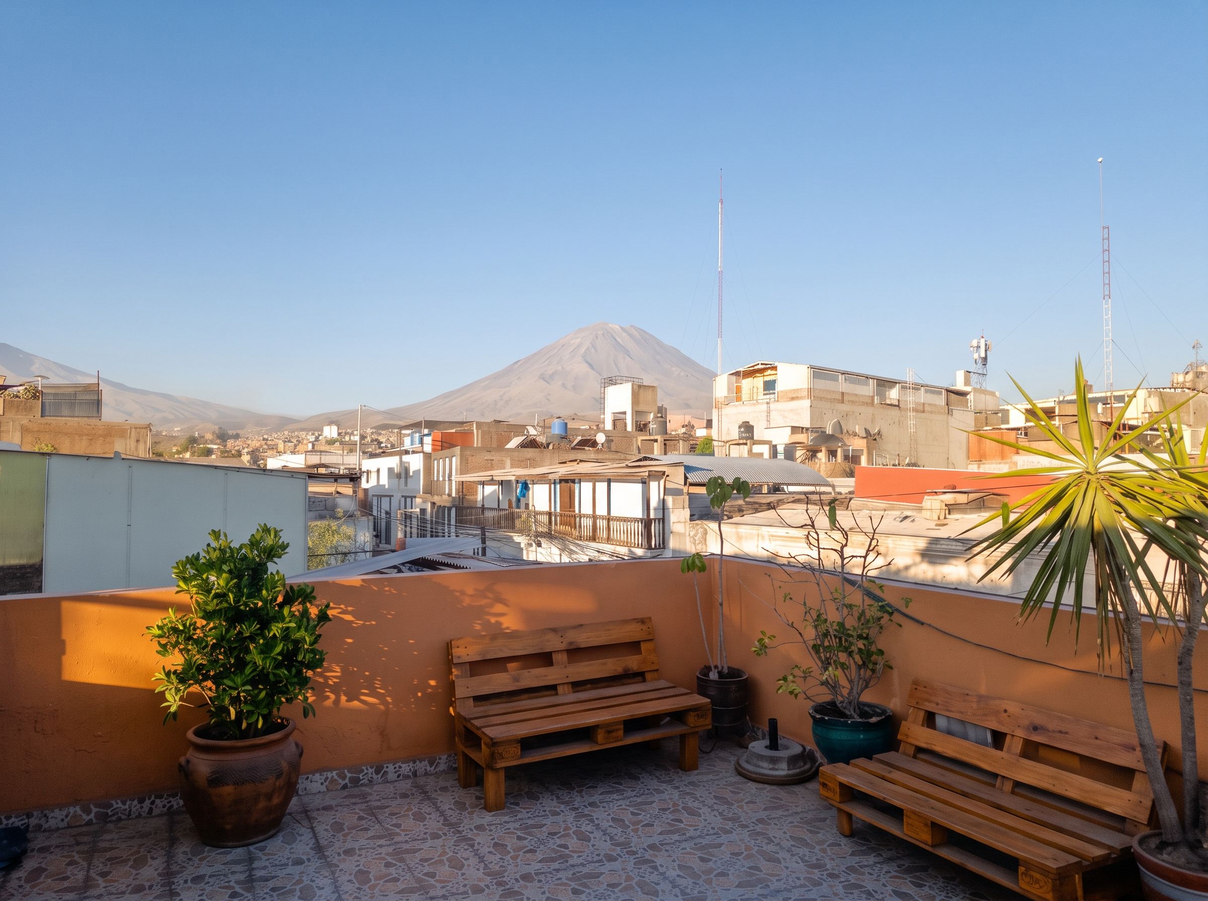 A rooftop terrace with a view of a cityscape and a mountain in the distance.