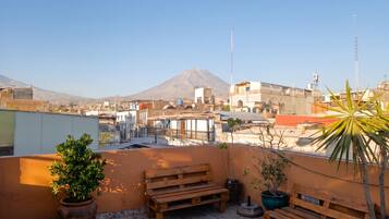 A rooftop terrace with a view of a cityscape and a mountain in the distance.