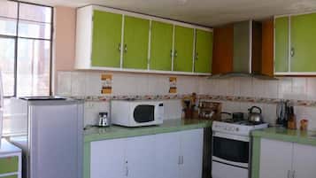 Una cocina con gabinetes verde y blanco, un microondas, una estufa y un refrigerador.