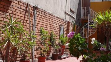 A courtyard with potted plants and a brick wall.