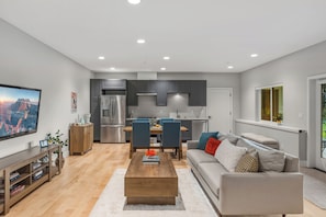 Un appartement moderne comprenant un salon, un coin repas, une cuisine et une grande fenêtre.