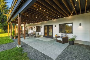 An outdoor patio area with a covered seating area, a table, and chairs.