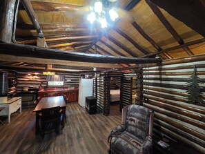 A log cabin interior with a dining area, kitchen, and a cozy seating area. - Black Bear Hideaway Cabin #6 (Clarington)