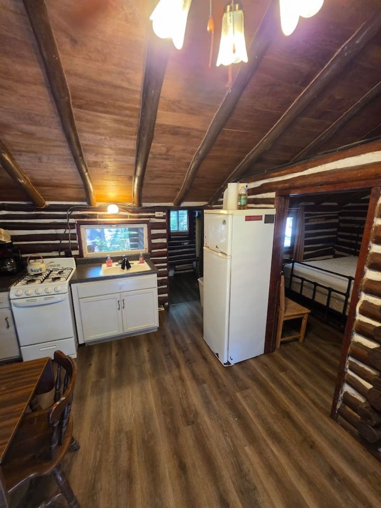 A cabin interior with a kitchen area, a dining table, and a bunk bed.