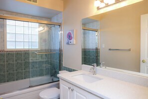 Un baño con ducha de vidrio, un lavamanos blanco y un inodoro.