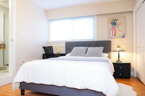 A bedroom with a bed, bedside tables, a lamp, a window, and a painting on the wall.