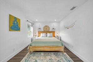 A bedroom with a wooden bed, white walls, a decorative ceiling medallion, bedside lamps, and a patterned rug. - Miami Home: Private Yard, Near Beaches & Dining (Miami)
