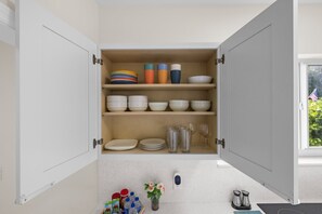 A kitchen with open cabinets containing dishes, glasses, and a digital scale. - Canal-View Terrace, Family-Friendly, 5 Min to MIA (Miami Springs)