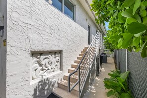 A staircase with a textured wall, a metal handrail, and a small decorative panel. - Canal-View Terrace, Family-Friendly, 5 Min to MIA (Miami Springs)