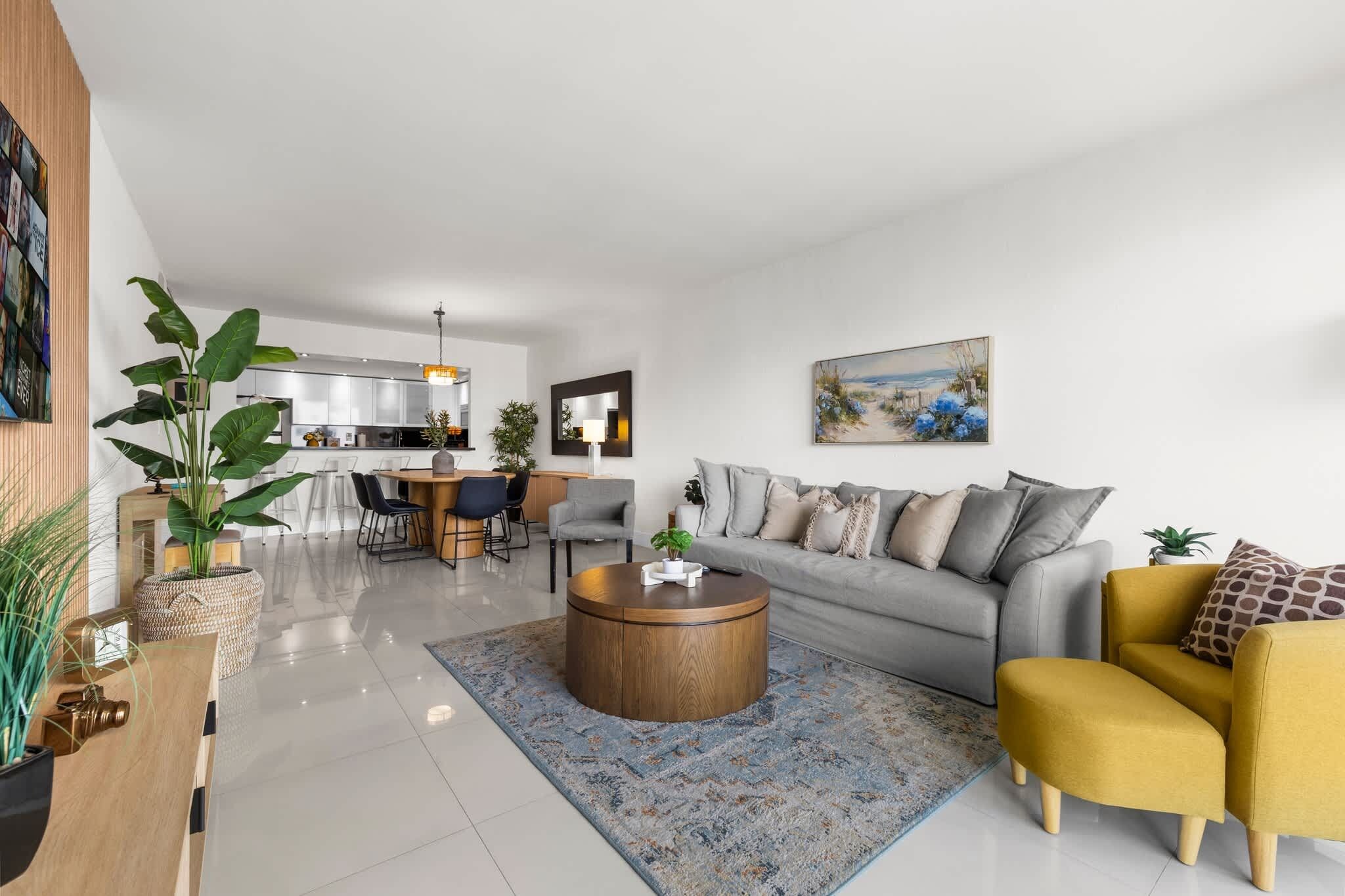A modern living room with a grey sofa, yellow armchair, and a round coffee table.