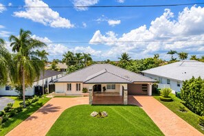 A residential property with a paved driveway, a covered patio, and a well-maintained lawn. - Miami Retreat: Pool, Game Room, Pet-Friendly Space (Miami)
