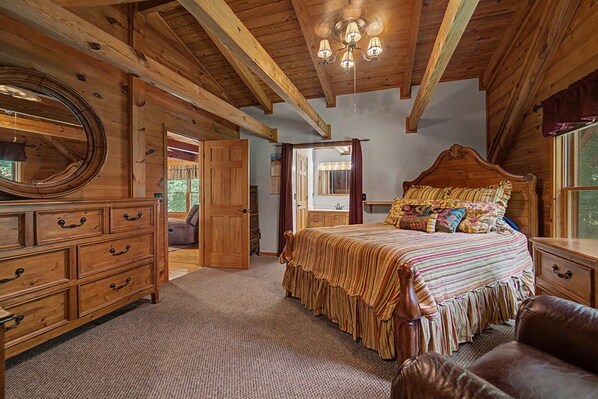 Une chambre à coucher avec un plafond en bois, un grand lit avec de nombreux oreillers, une commode et un miroir.