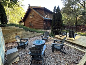 Una cabaña con terraza, mobiliario exterior y una chimenea.