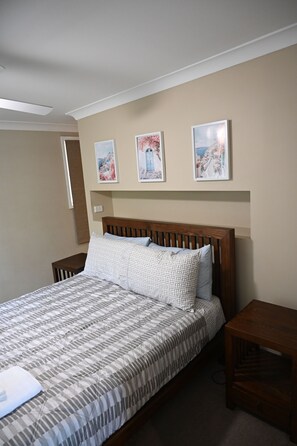 A bedroom with a bed, wooden headboard, and three framed pictures on the wall. - Lakeview Retreat, Deck & Room to Unwind | Get Back 2 Basics Rathmines (Rathmines)