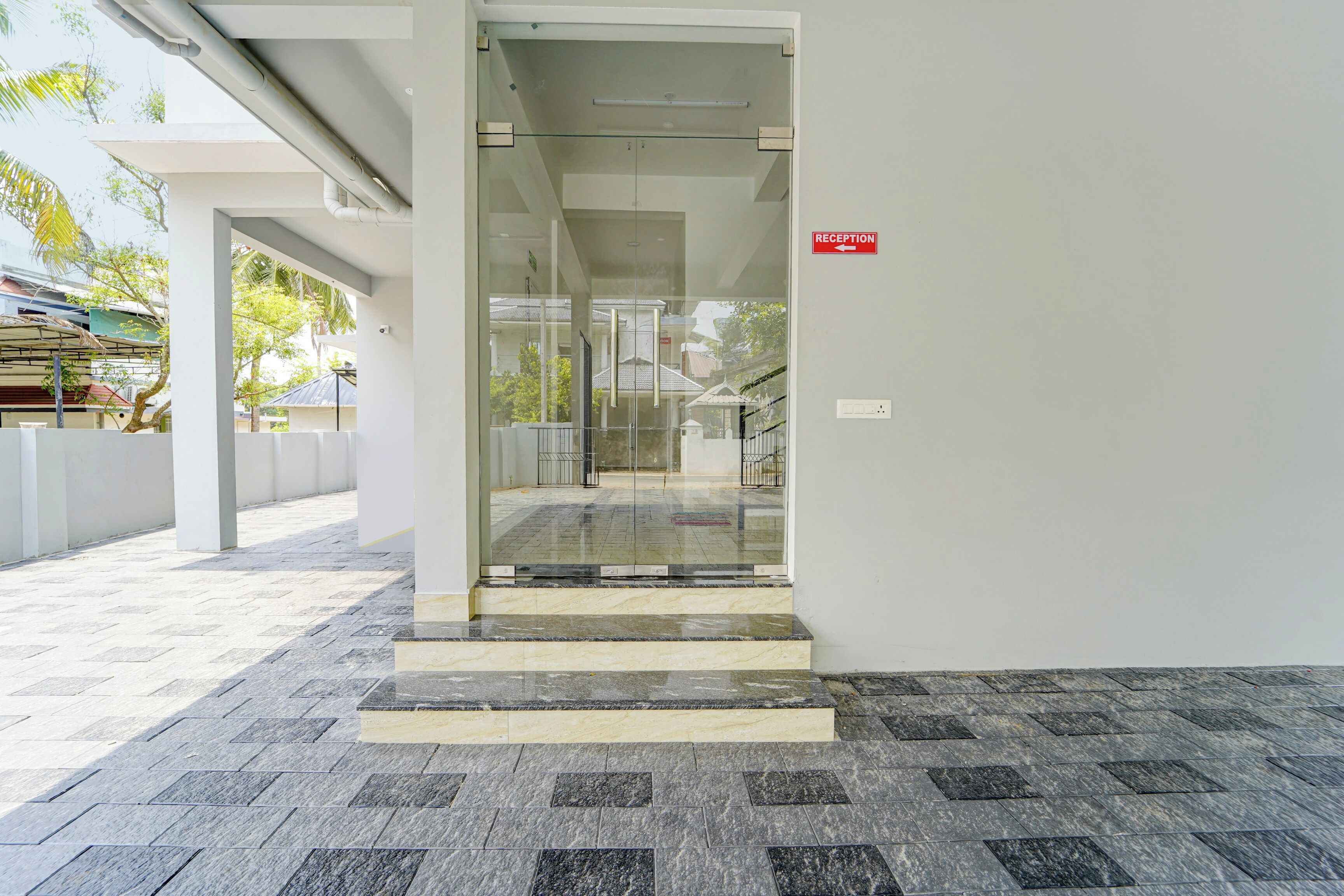 A reception area with a glass door, a reception desk, and a staircase leading to an upper level.