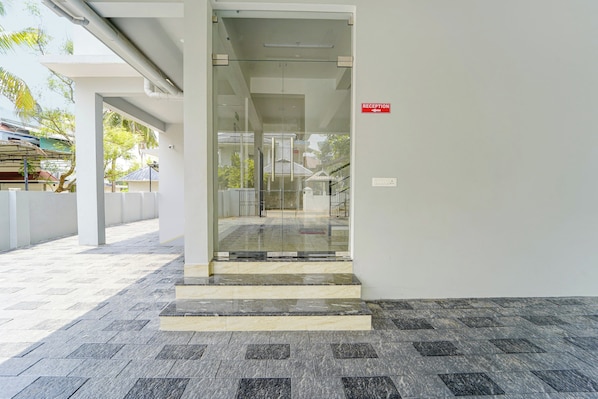 A reception area with a glass door, a reception desk, and a staircase leading to an upper level.