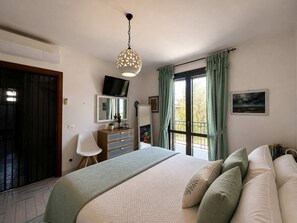 A bedroom with a bed, a dresser, a television, and a window with curtains. - The Secret Garden, villa with private garden (San Vito Lo Capo)