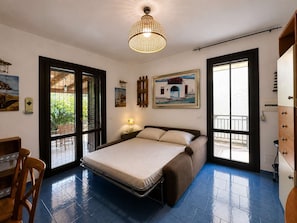 A bedroom with a bed, a desk, and a chair. There are two windows and a door. - The Secret Garden, villa with private garden (San Vito Lo Capo)