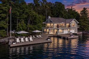 Une maison au bord du lac, avec un quai, un espace salon extérieur et un drapeau.