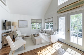 A spacious living room with a large white sofa, a television, and a fireplace. - Island on Lake Joe! Cozy and rustic 5Bed 3Bath with 399' of shoreline! (MacTier)