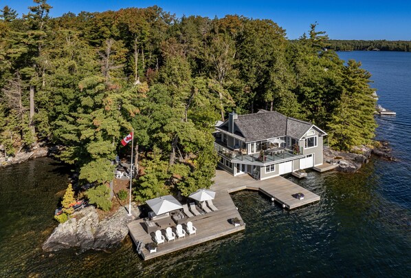 Une maison avec une jetée qui s’avance sur un lac, entourée d’une forêt dense.