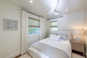 A modern bedroom with a large bed, two windows with blinds, a bedside table with a lamp, and a wall-mounted light fixture. - Island on Lake Joe! Cozy and rustic 5Bed 3Bath with 399' of shoreline! (MacTier)